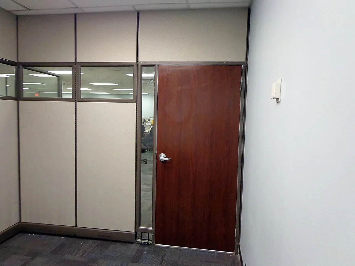 Full-height modular wall with wood door and glass creating a private office