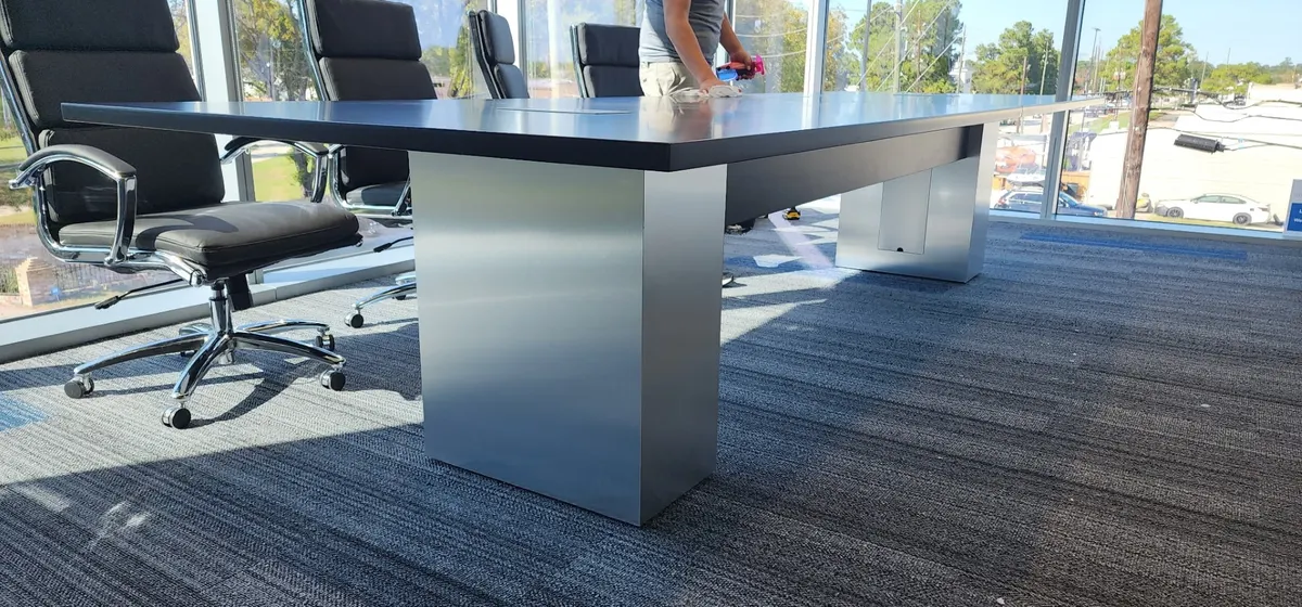 Dark conference table with brushed metal base by window wall