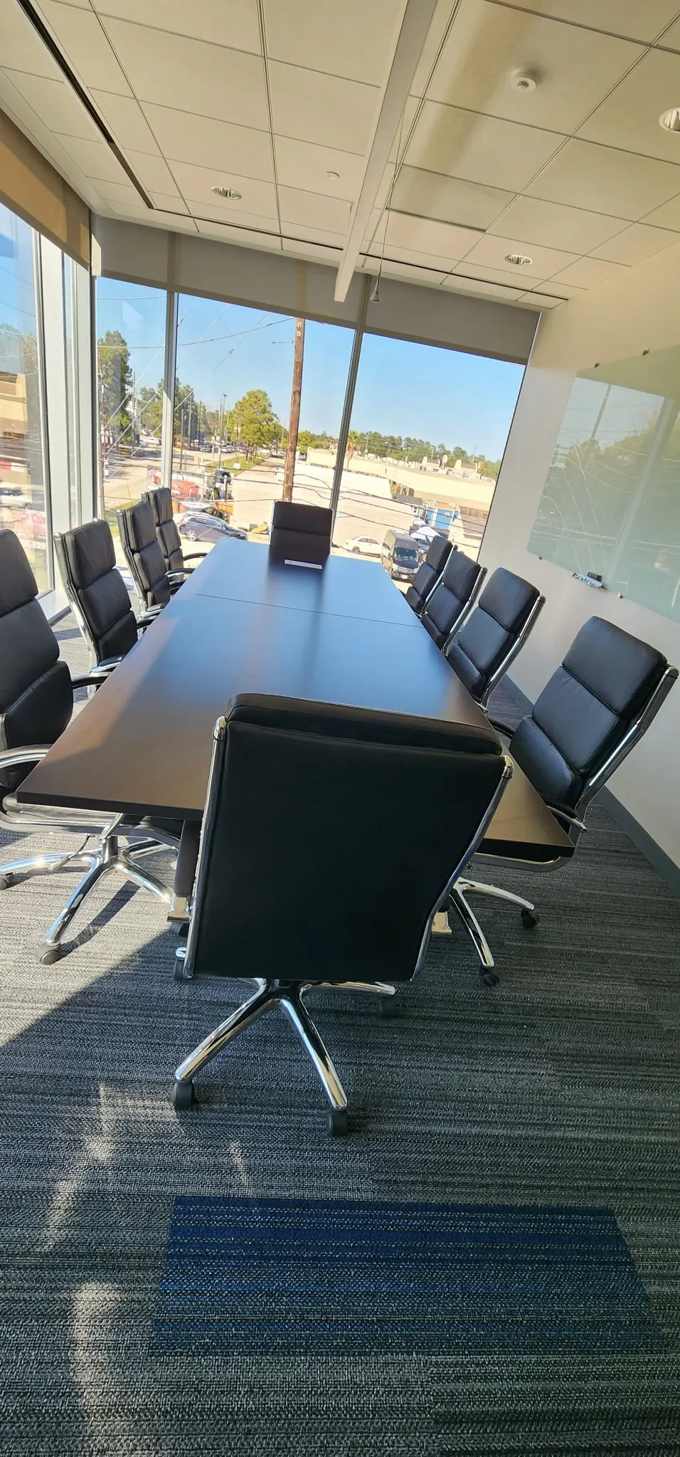 Boardroom conference table with black leather chairs and floor-to-ceiling windows