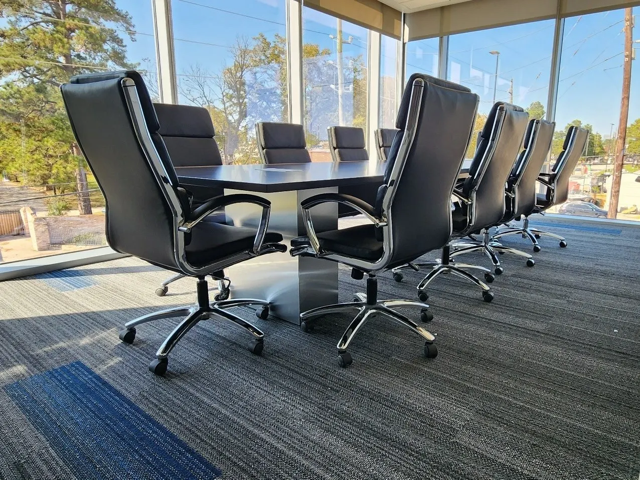 Custom 12-foot conference table with metal base built by New Space, set in a boardroom with executive seating
