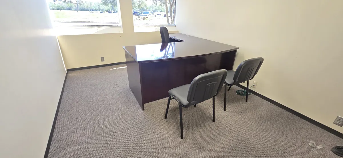 Furnished office with dark desk and guest chairs