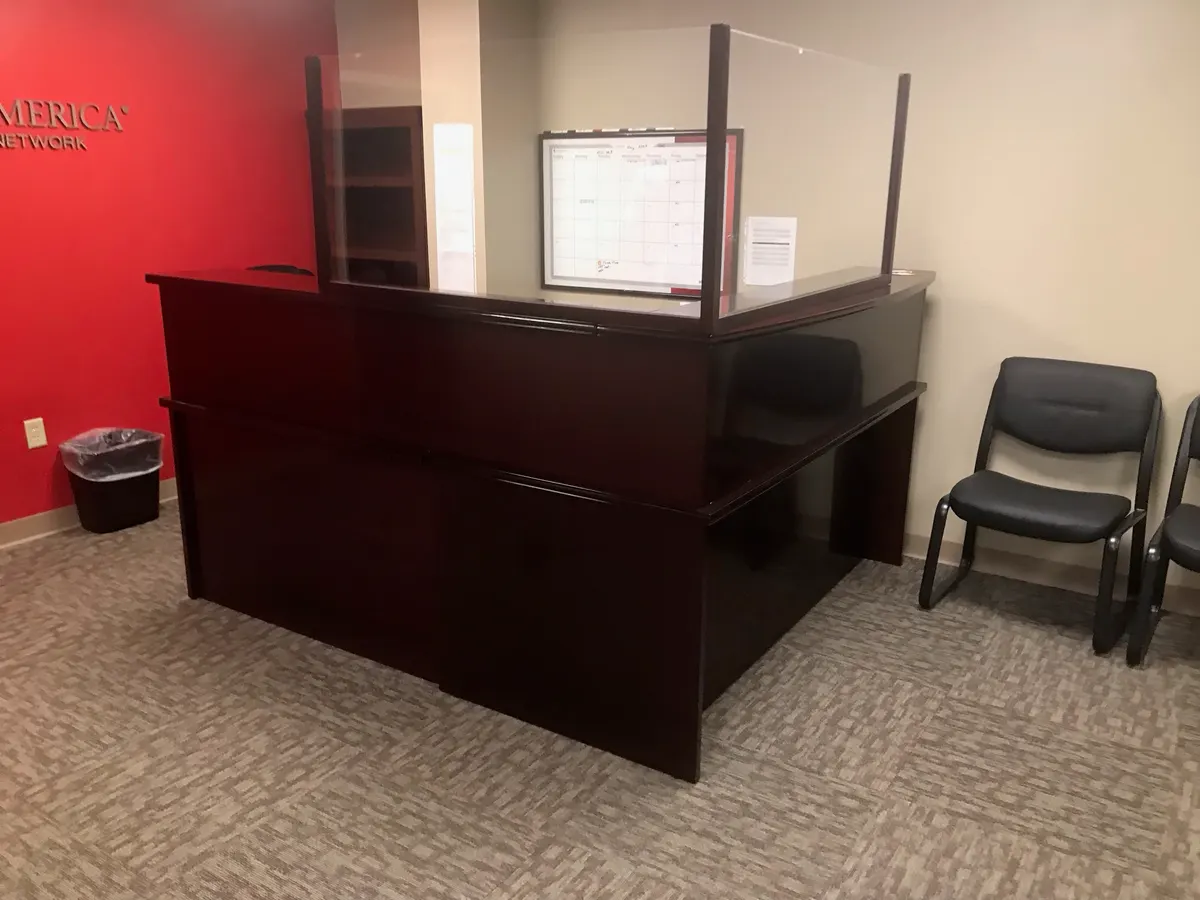 Office reception area with dark wood desk and whiteboard wall