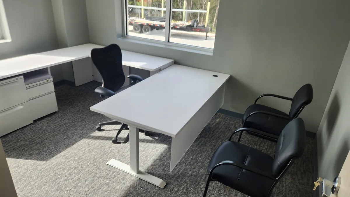Workstation with height-adjustable desk section fitted to the room
